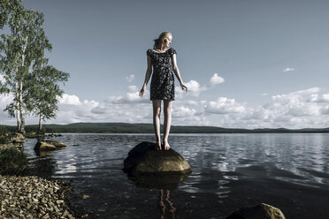 Frau in voller Länge auf einem Felsen im Fluss stehend gegen bewölkten Himmel - CAVF34351