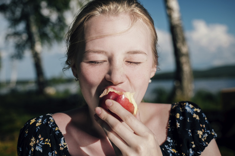 Frau isst Apfel an einem sonnigen Tag, lizenzfreies Stockfoto