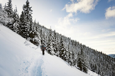 Low angle view of man hiking on snow covered mountain against sky - CAVF34407