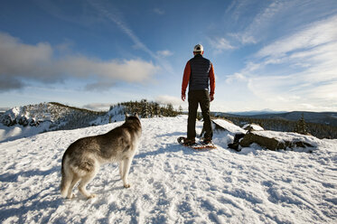 Rückansicht eines Mannes mit Hund auf einem schneebedeckten Feld gegen den Himmel - CAVF34408