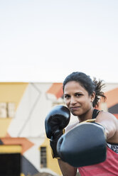 Porträt einer selbstbewussten Boxerin vor dem Fitnessstudio bei klarem Himmel - CAVF34431