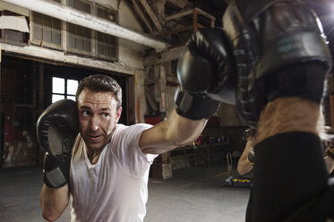 Entschlossener männlicher Boxer beim Training im Fitnessstudio - CAVF34434