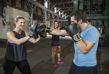 Glückliche Boxerin beim Training mit einem Freund im Fitnessstudio - CAVF34436