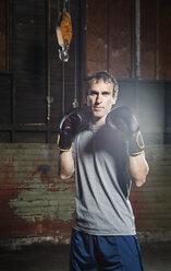 Porträt eines selbstbewussten männlichen Boxers, der in einer Turnhalle steht - CAVF34440