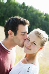 Young man kissing girlfriend's cheek - FOLF09148