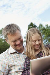 Vater und Tochter benutzen ein digitales Tablet im Freien - FOLF09166