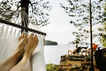 Young woman relaxing in hammock by lake - FOLF09196