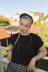 Porträt einer jungen, selbstbewussten Frau im Sommer, die auf einem Balkon steht - FOLF09207