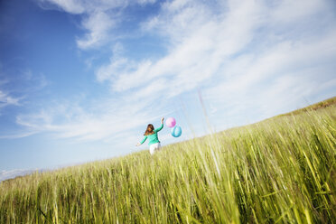 Girl with balloons running in field - FOLF09303