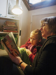 Großmutter liest einem Kleinkind ein Buch vor - FOLF09356