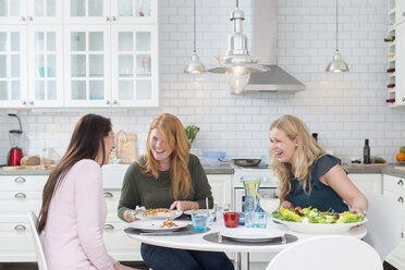 Drei lachende Frauen am Küchentisch - FOLF09360