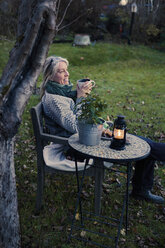 Ältere Frau entspannt sich mit einer Tasse Kaffee im Hinterhof - FOLF09382