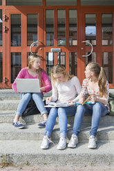 Mädchen im Teenageralter sitzen vor der Schultür - FOLF09399