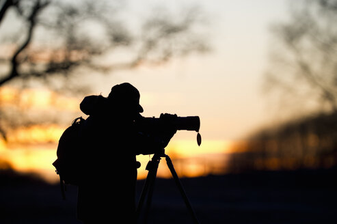 Silhouette eines Mannes mit seiner Kamera bei Sonnenuntergang - FOLF09528