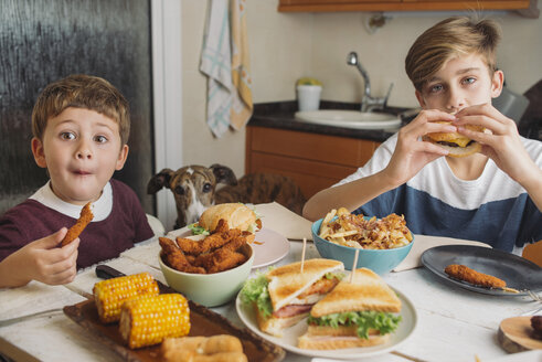 Zwei Jungen mit Hund genießen amerikanisches Essen am Esstisch zu Hause - SKCF00394