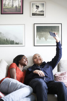Mutter und Sohn machen ein Selfie mit dem Mobiltelefon auf dem Sofa zu Hause - MASF00028