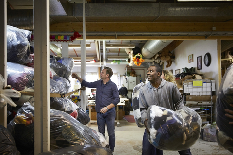 Coworkers stacking plastic sacks in warehouse stock photo