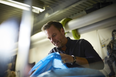 Low angle view of mature worker searching in plastic bag at warehouse stock photo