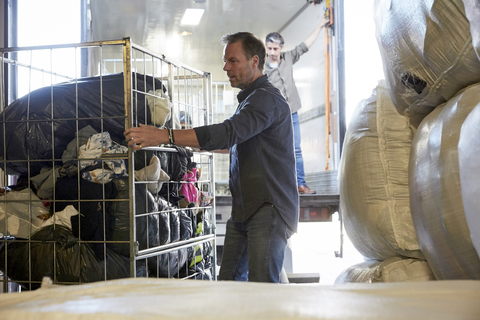 Mature volunteer unloading semi-truck at warehouse stock photo