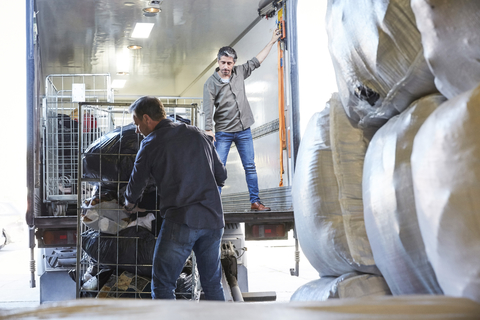 Mature coworkers unloading semi-truck at warehouse stock photo