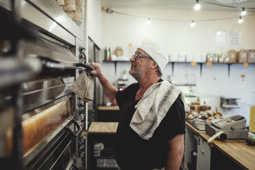 Bäckermeister vor dem Ofen in der Bäckerei - MASF00078