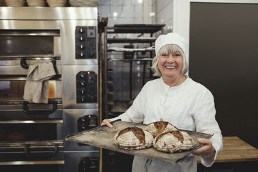 Lächelnder Bäcker mit frisch gebackenen Broten in einer Bäckerei - MASF00088