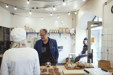 Männlicher Kunde kauft in einer Bäckerei Lebensmittel vom Besitzer - MASF00094