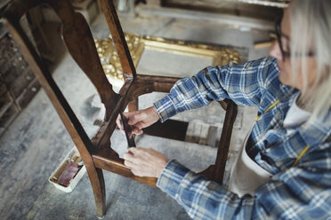 Blick von oben auf einen Handwerker, der in einer Werkstatt einen Holzstuhl herstellt - MASF00125