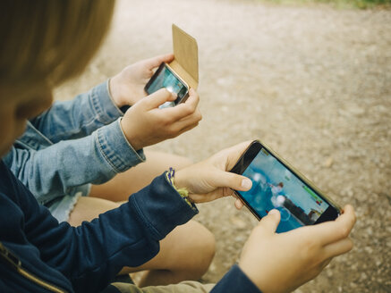 Hochformatige Ansicht von Geschwistern beim Spielen auf dem Smartphone - MASF00132