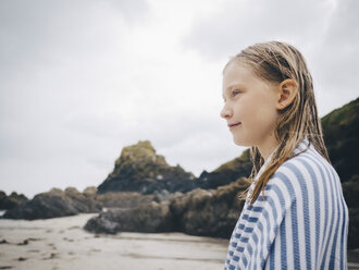 Seitenansicht eines blonden Mädchens, eingewickelt in ein Handtuch, das am Strand vor dem Himmel steht - MASF00142