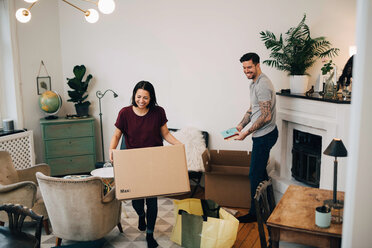 Glückliches Paar beim Auspacken von Kartons im Wohnzimmer des neuen Hauses - MASF00154