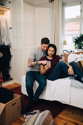 Couple using mobile phone while resting on bed in bedroom - MASF00158