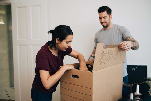 Mann hilft Frau beim Auspacken einer Kiste im neuen Haus - MASF00198