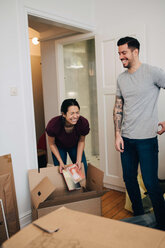 Couple enjoying while unpacking boxes in new apartment - MASF00199