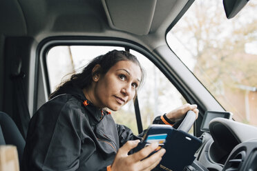 Frau hält Handy und schaut weg, während sie im Lieferwagen fährt - MASF00261
