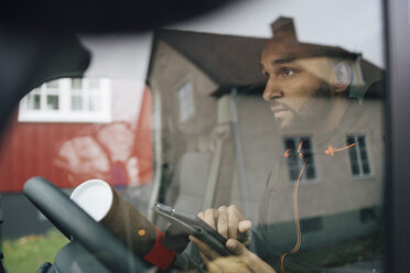 Mann mit digitalem Tablet durch die Windschutzscheibe eines Lieferwagens gesehen - MASF00265