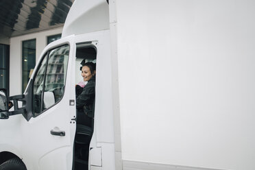 Lächelnde Mitarbeiterin beim Schließen der Tür eines weißen Lieferwagens - MASF00278