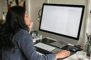 Side view of businesswoman using computer while sitting at home office - MASF00304