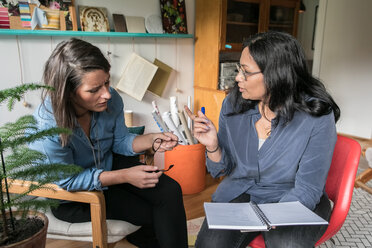 Weibliche Kollegen diskutieren über ein Buch, während sie im Home Office sitzen - MASF00309