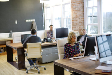 Colleagues working at desks in office - CAVF34449