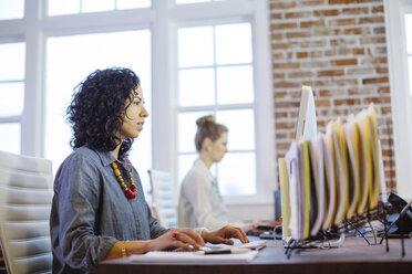 Weibliche Kollegen arbeiten am Schreibtisch im Büro - CAVF34456