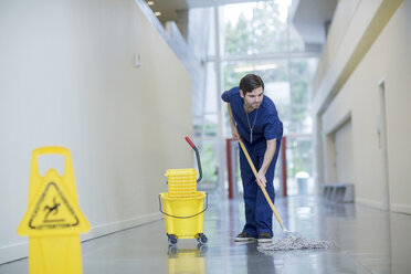 Männlicher Arbeiter beim Reinigen des Fußbodens im Krankenhauskorridor - CAVF34529