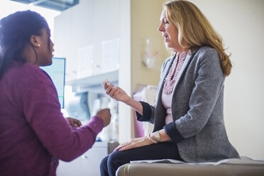 Patientin zeigt verschreibungspflichtige Medikamente an Ärztin im Behandlungszimmer - CAVF34567