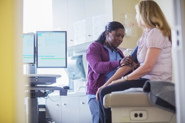 Ärztin bei der Untersuchung eines Patienten mit Stethoskop in einem medizinischen Raum - CAVF34568