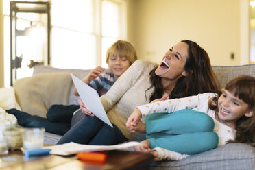 Verspielte Mutter mit Kindern, die zu Hause auf dem Sofa sitzen - CAVF34599