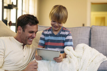 Father with son using tablet computer while sitting at home - CAVF34605