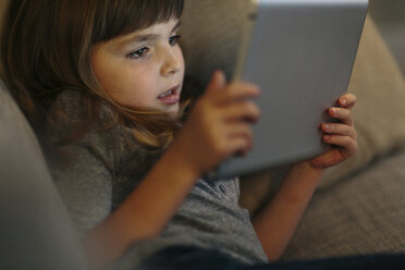 Hohe Winkel Ansicht des Mädchens mit Tablet-Computer, während auf dem Sofa zu Hause liegen - CAVF34609