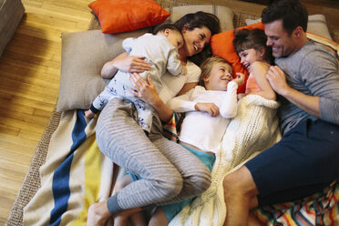 Hochformatige Ansicht von Eltern mit Kindern, die zu Hause auf dem Teppich schlafen - CAVF34613