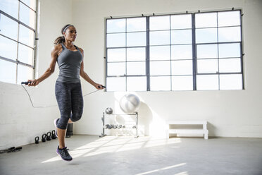 Weibliche Athletin springt mit einem Springseil im Fitnessstudio - CAVF34643