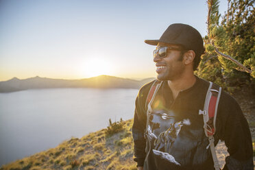 Lächelnder Wanderer auf einem Berg im Crater Lake National Park bei Sonnenuntergang - CAVF34656